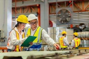 Man mentor teaching Female employees trainee operating machine looking monitors and check Production process machinery.