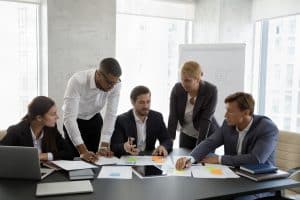Group of focused young serious multiracial colleagues analyzing financial paper documents