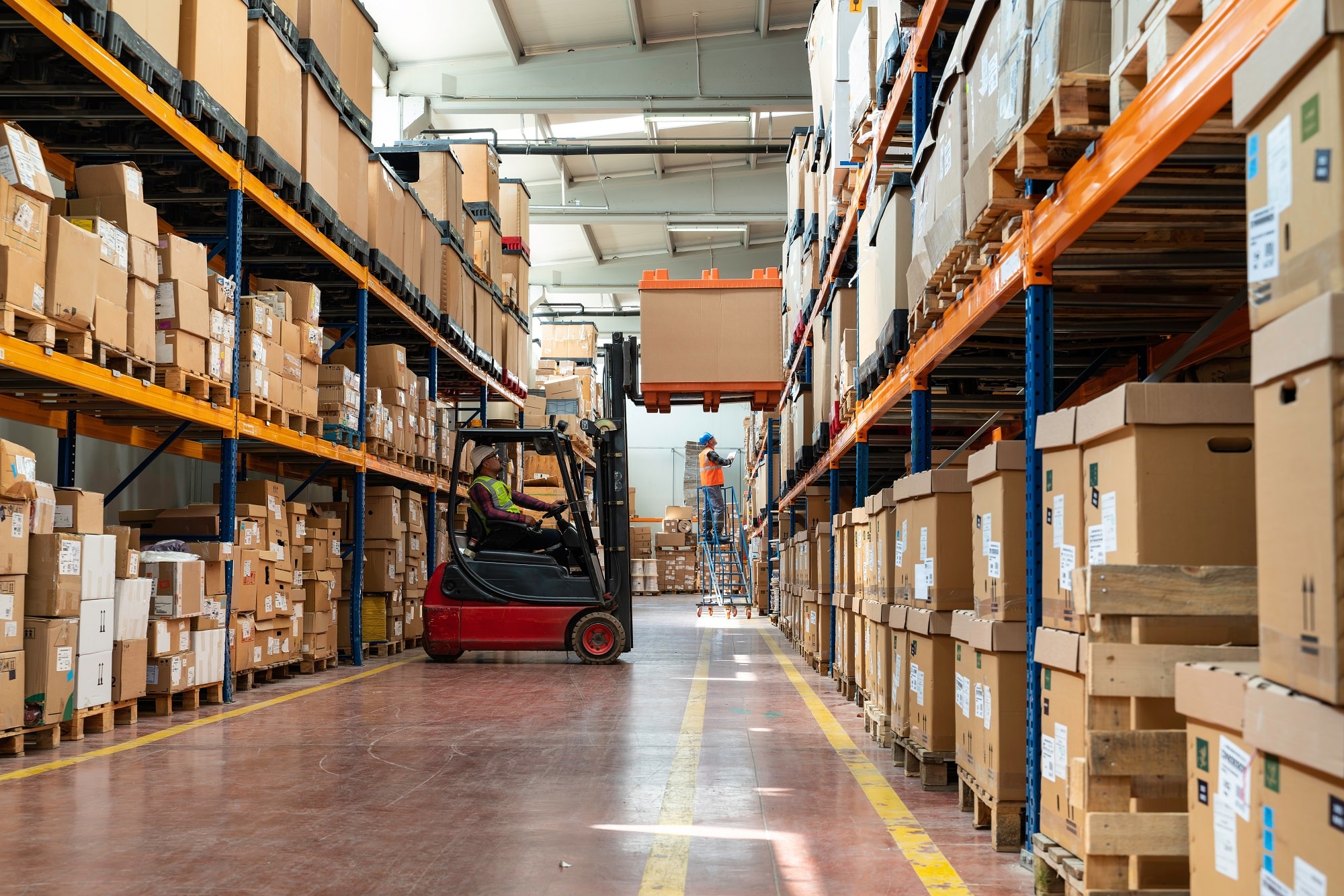 Manager wearing hard hat with digital tablet counts merchandise in warehouse