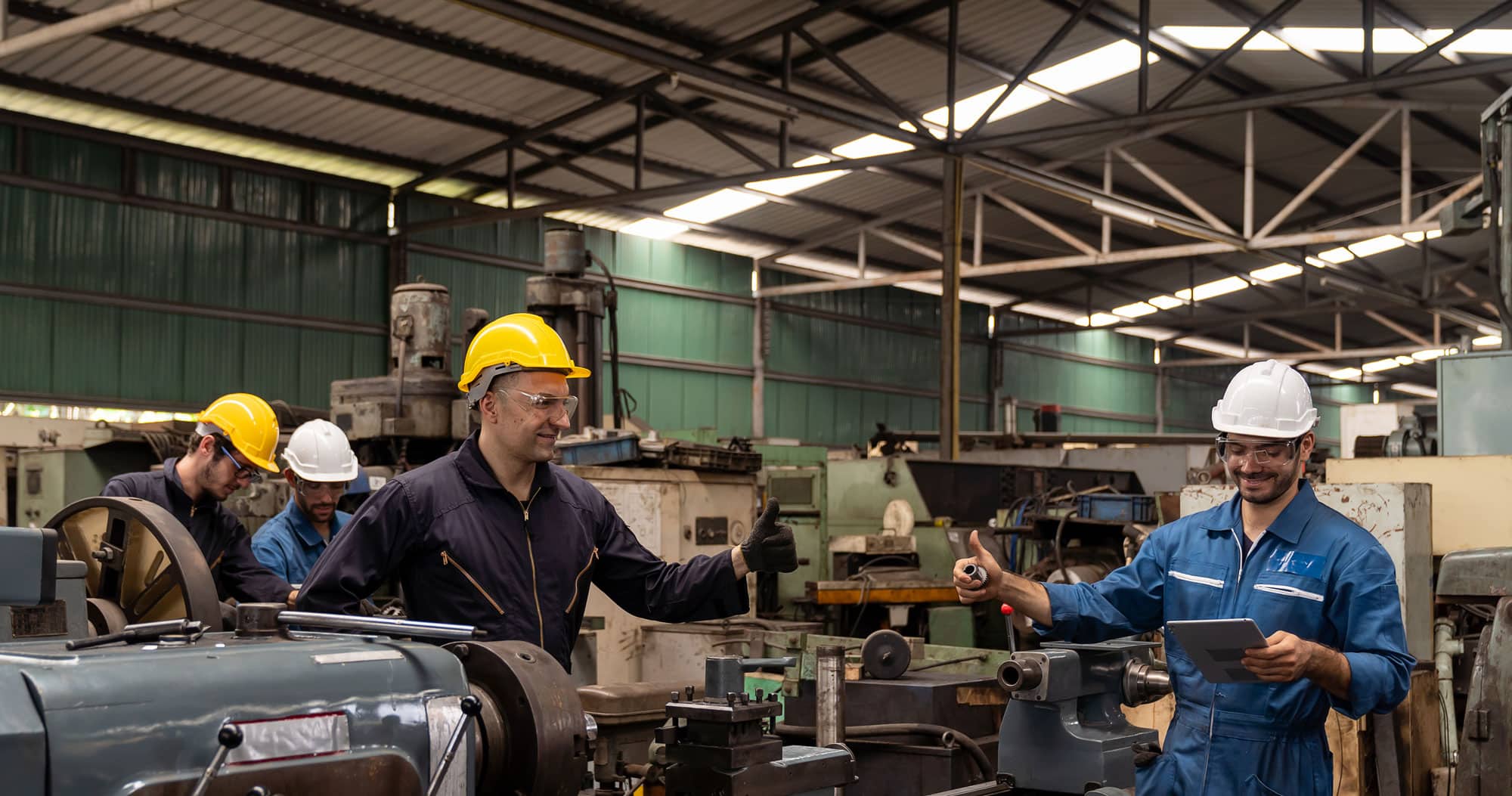 Team of Manufacturing Workers in Safety Gear Collaborating in Factory Workshop