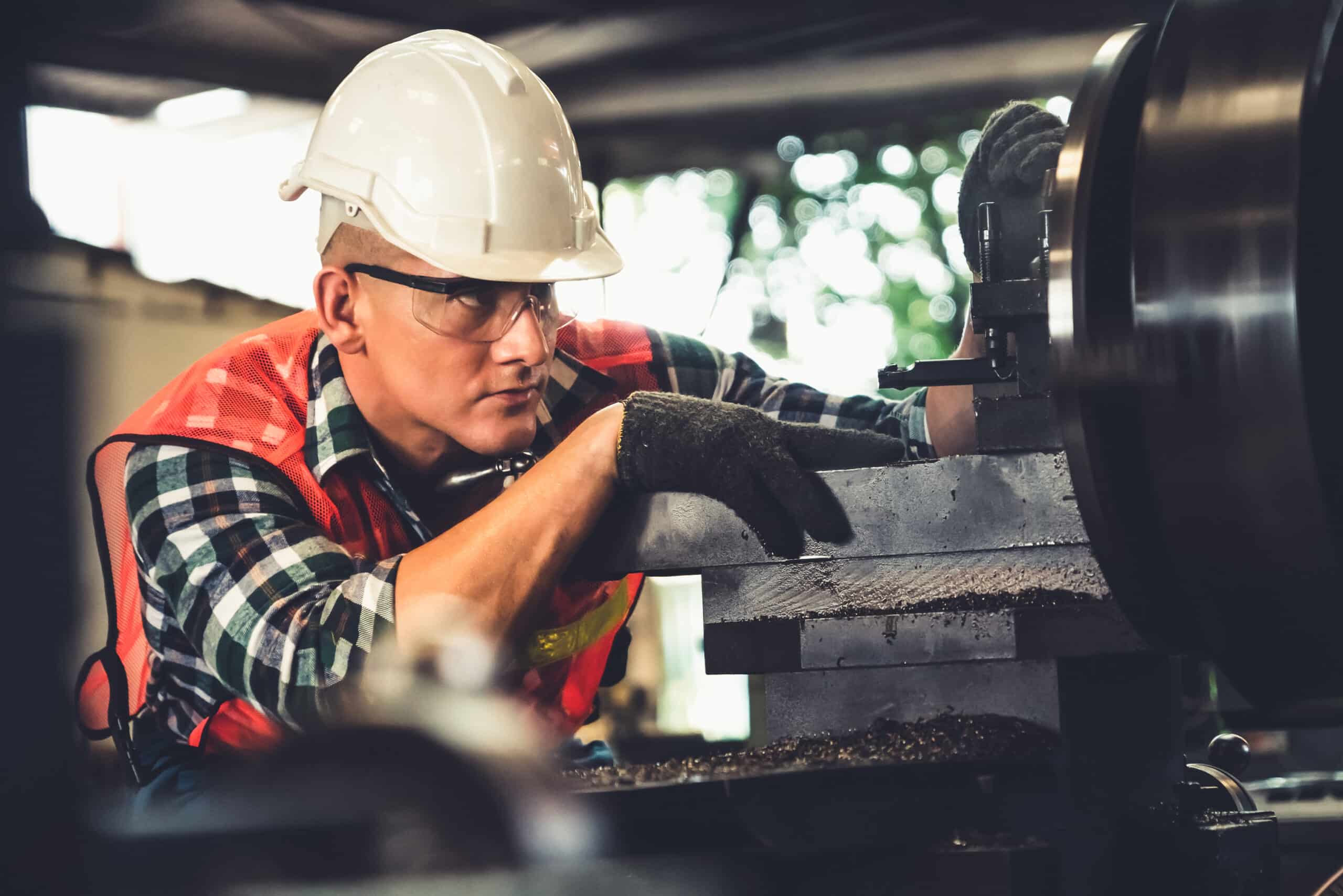 Focused manufacturing worker in safety gear operating machinery in industrial facility, demonstrating skills for temp-to-perm career growth.