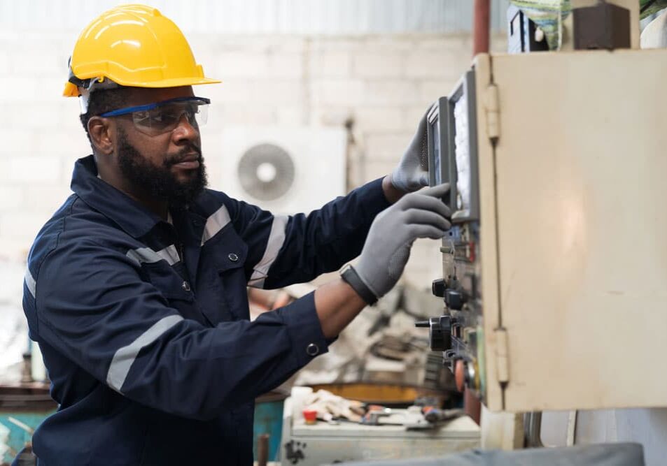 CNC Machinist in Safety Gear Operating Industrial Machinery in Factory Workshop
