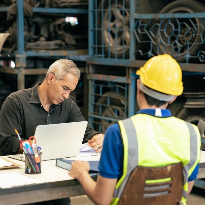 Factory manager looking at the paper with young engineer
