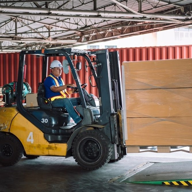 warehouse worker driving forklift for loading pallets