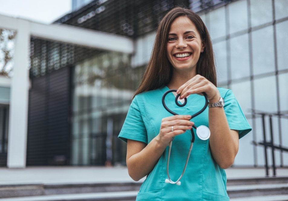 A joyful Caucasian female nurse forms a heart with her stethoscope A joyful Caucasian female nurse forms a heart with her stethoscope