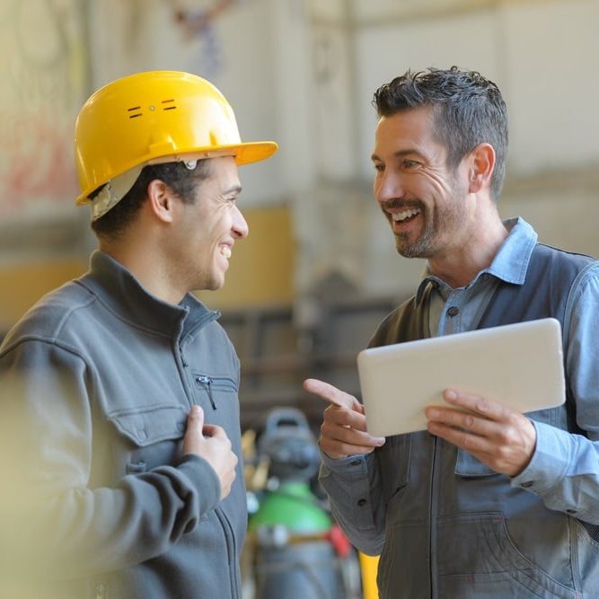 Manufacturing employees talking and laughing at the factory Manufacturing employees talking and laughing at the factory