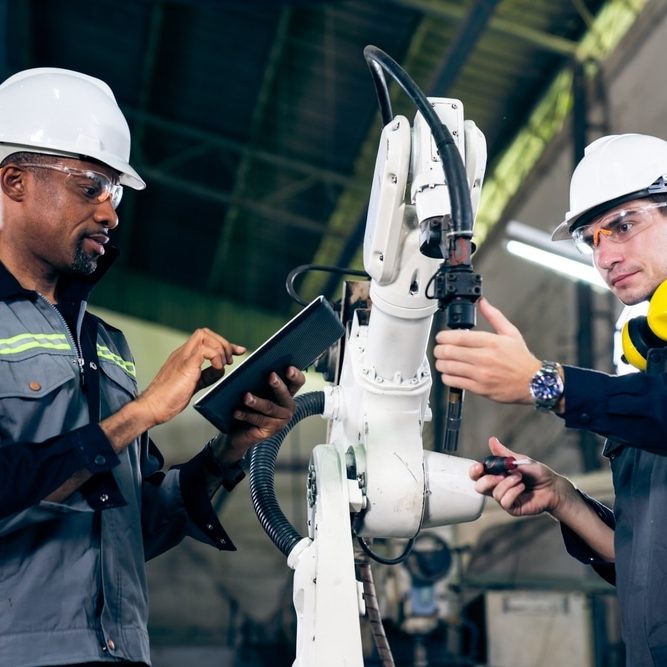 Factory workers working with adept robotic arm in a workshop
