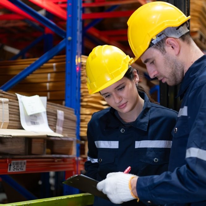 Both of warehouse staff working together in a large paper warehouse using a tablet computer