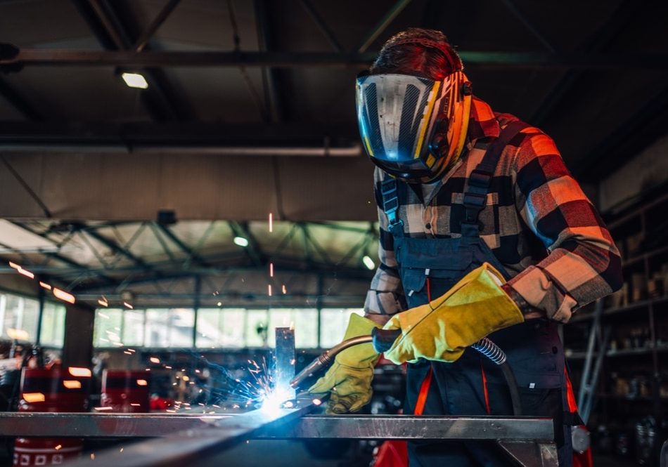 Dedicated,Young,Worker,Welding,A,Piece,Of,Metal,While,Assembling Dedicated young worker welding a piece of metal