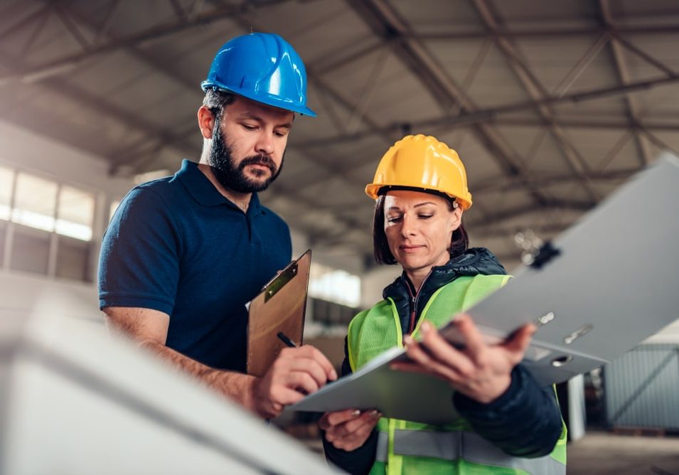 Factory worker signing document in industrial hall Factory worker signing document in industrial hall